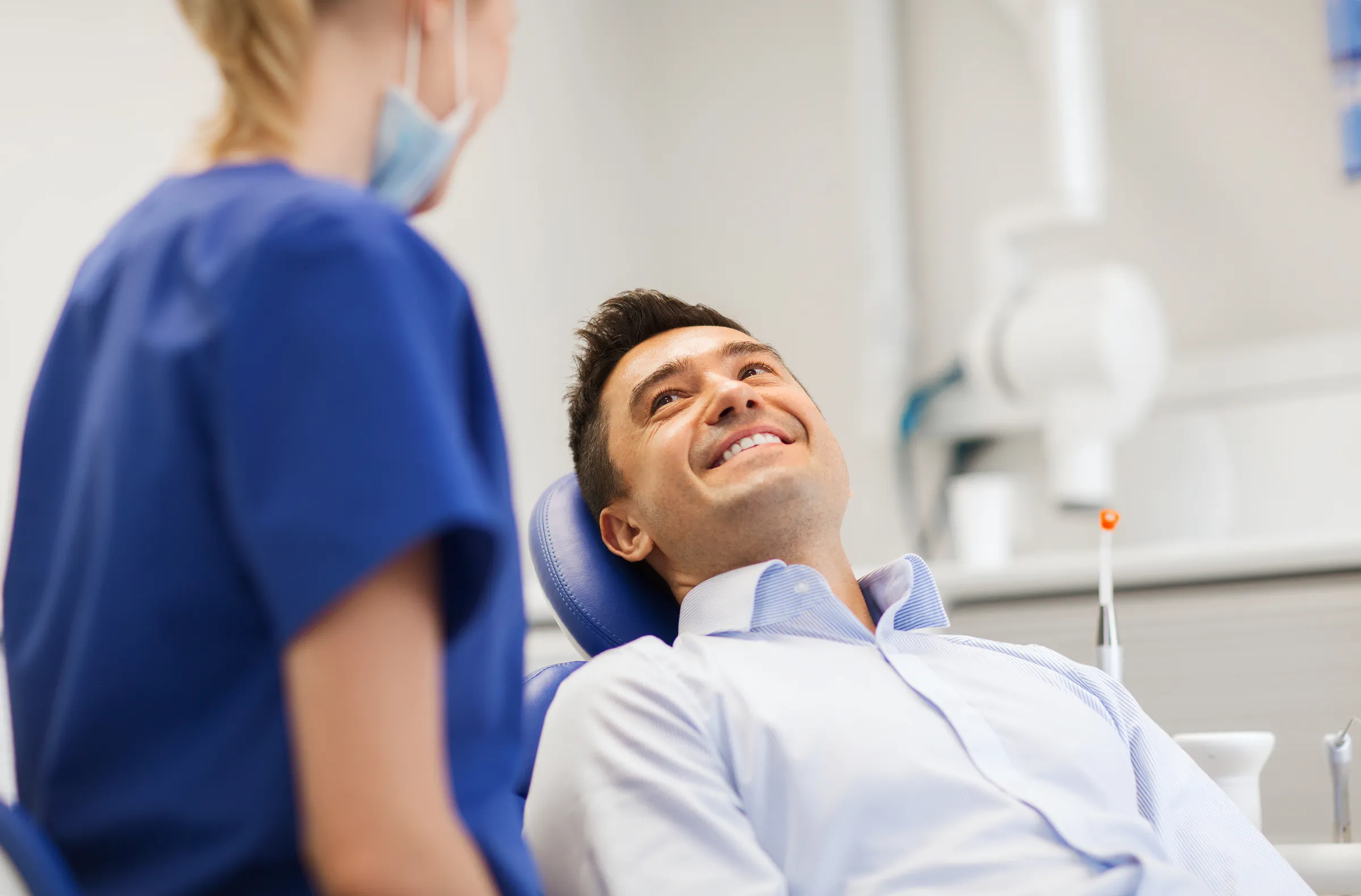 A smiling man relaxing in the dental chair while a team member prepares for his exam
