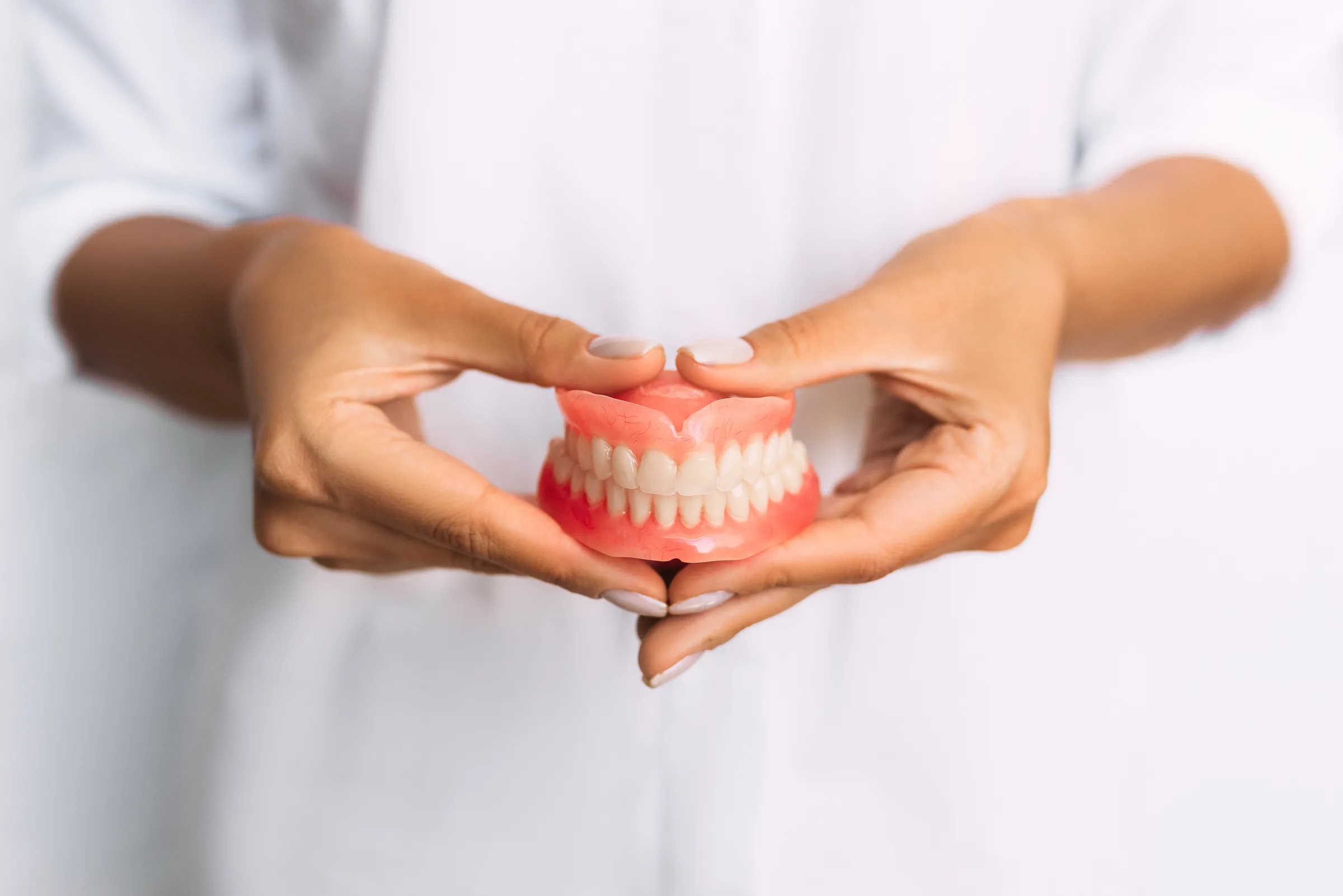 Hands holding a complete upper and lower denture