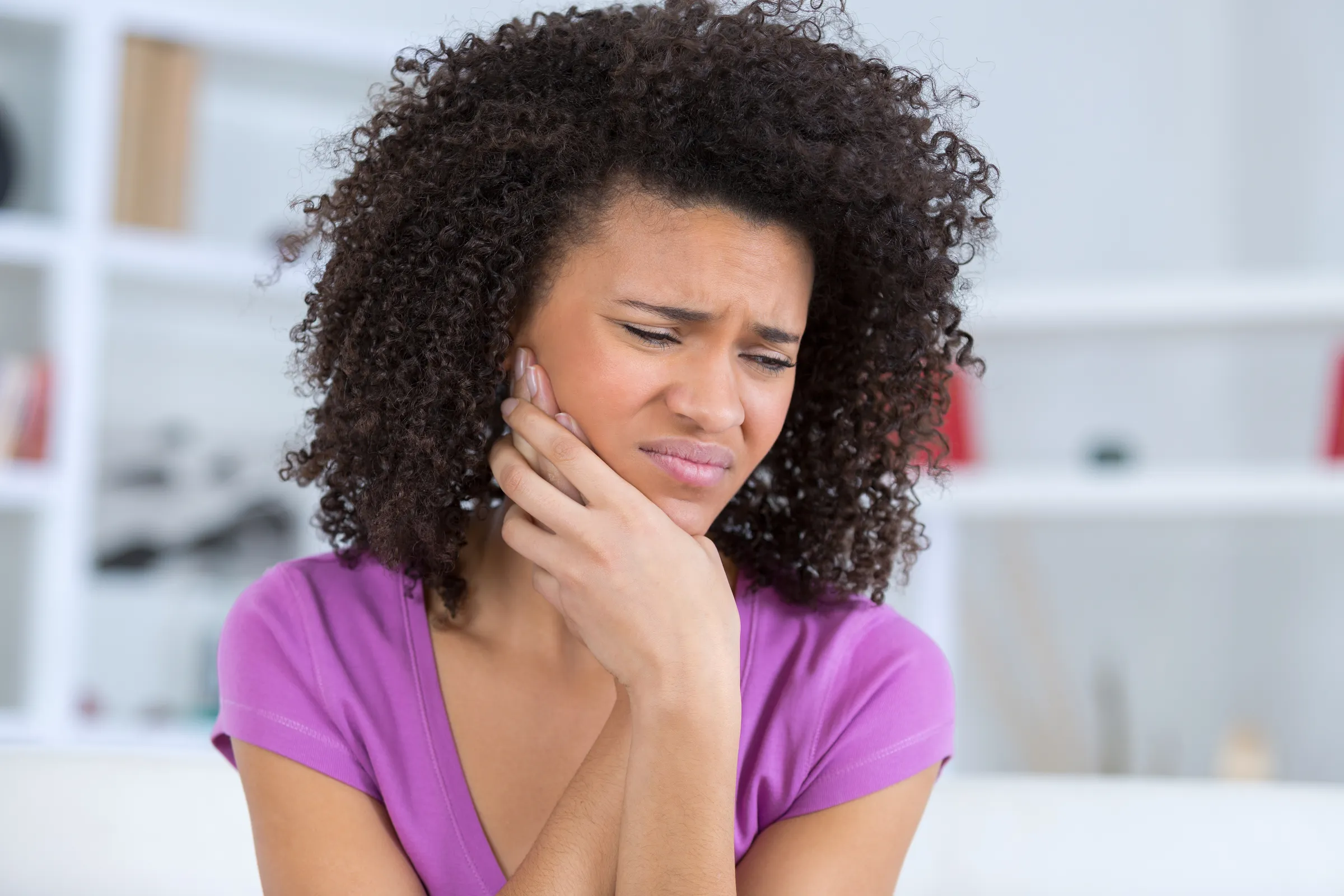 A woman holding her jaw in pain from a toothache