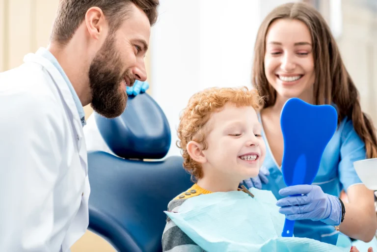 A young boy in the dental chair with a dentist and his smiling mother
