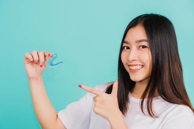 A smiling woman holding up a clear retainer