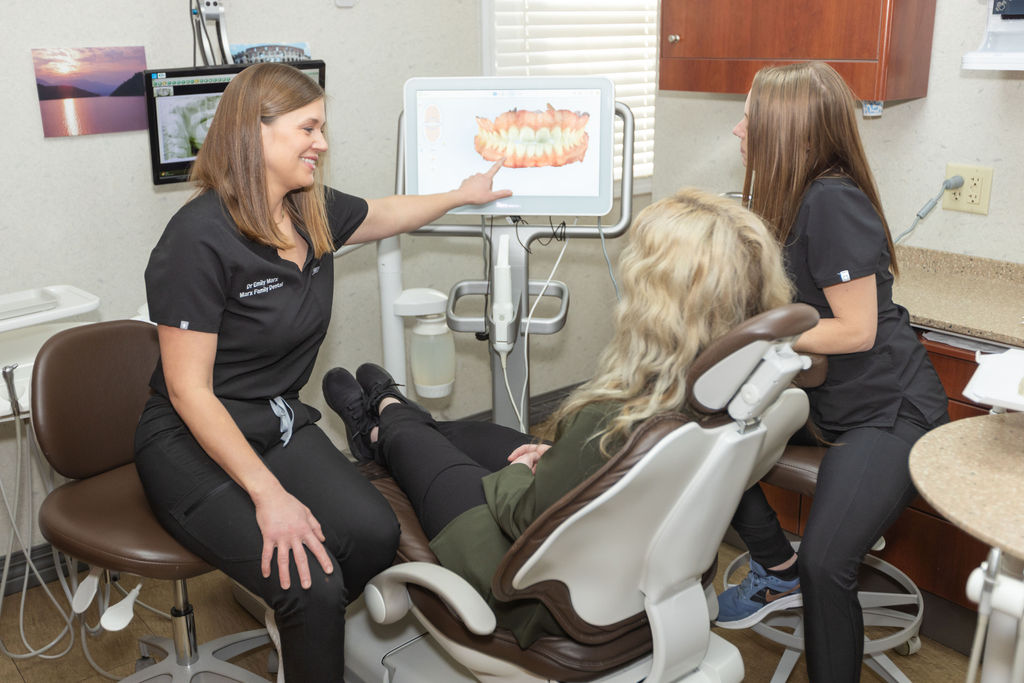 A team member showing a seated patient a digital scan of her teeth