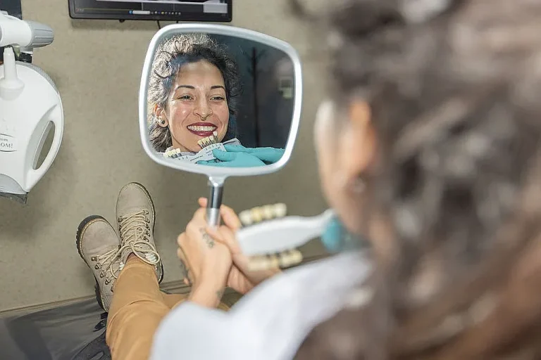 A patient smiling at her reflection in a hand mirror